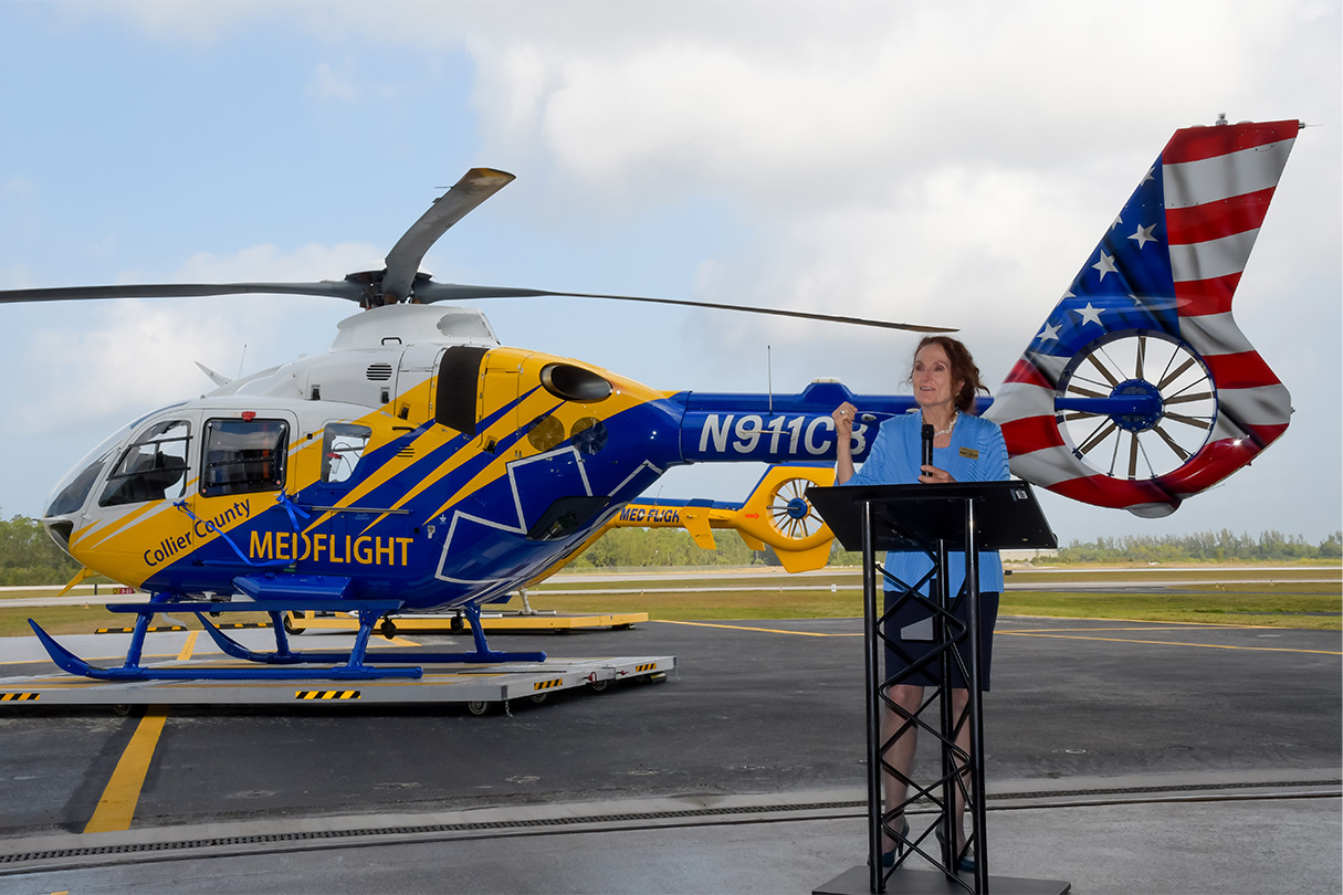 Penny Taylor speaks in front of a helicopter